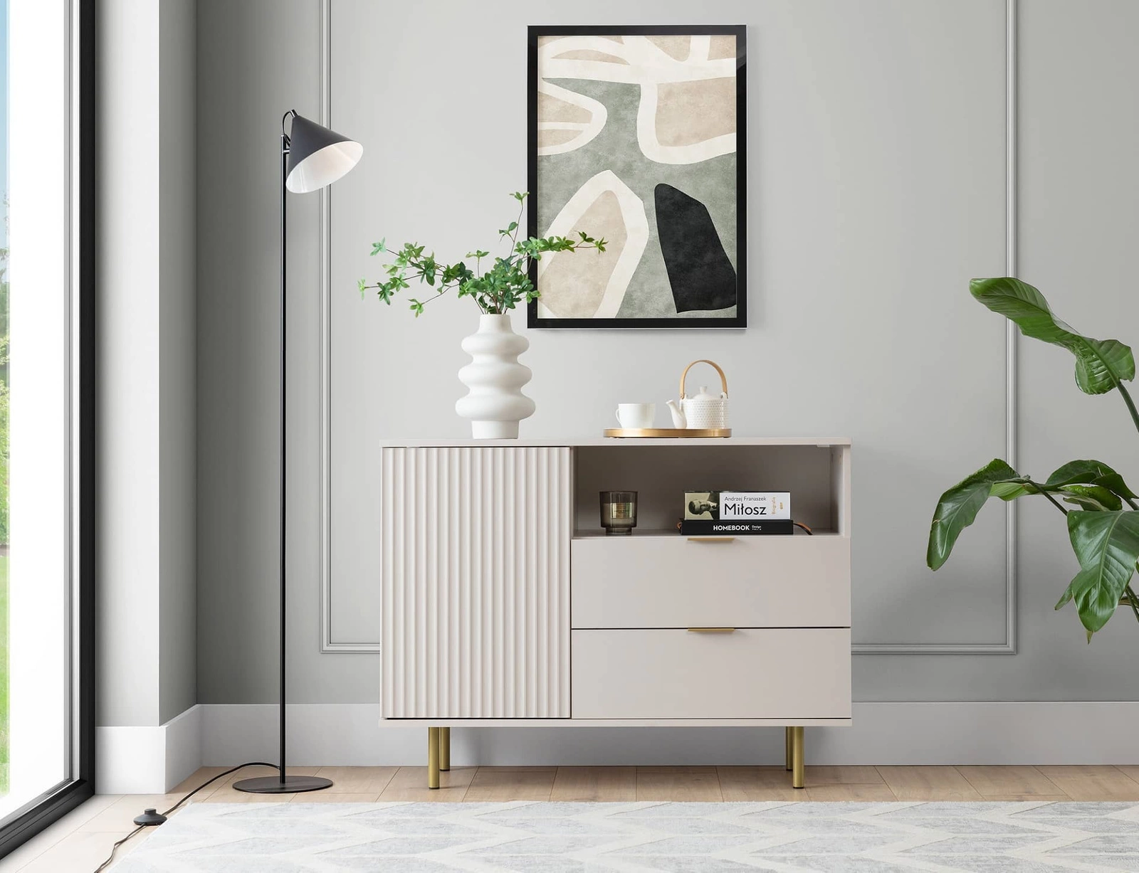 Sula kumode 107 cm bēšā krāsā, eleganta un funkcionāla kumode ar dekoratīvu rievotu priekšpusi, kas bagātināta ar metāla rokturiem.